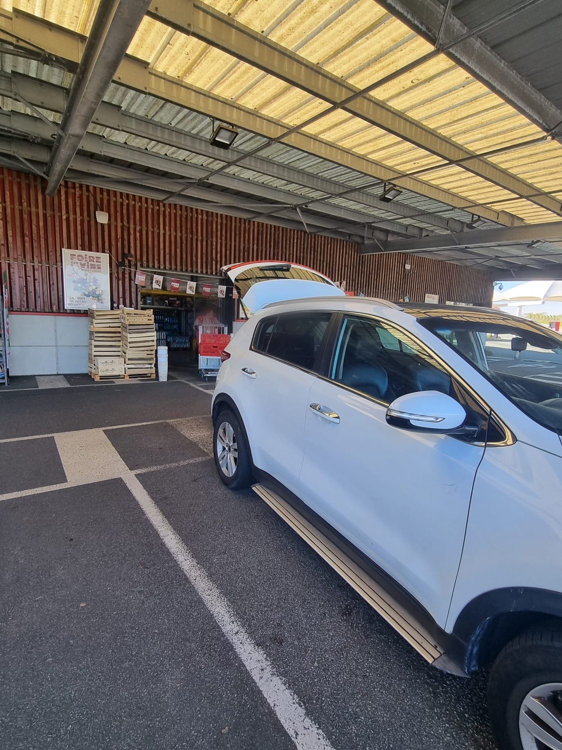 An Auchan staff member bringing an order out to the car at the Drive collection bay